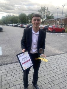 Image of Gerrard Ashcroft stood smiling holding his certificate and award.